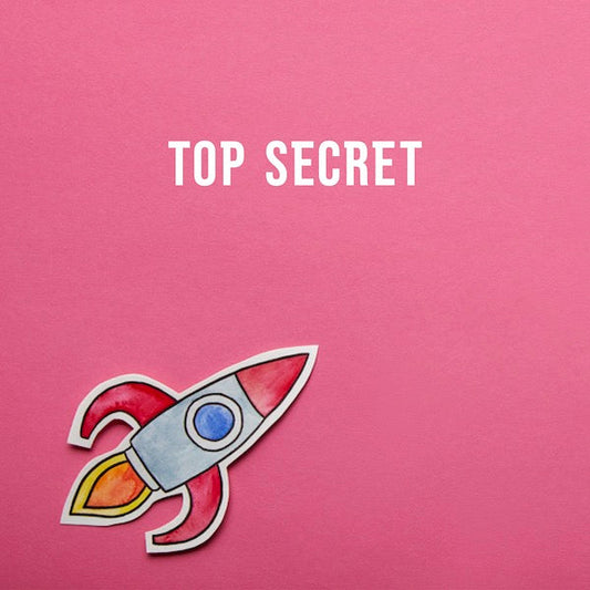 A paper spaceship against a background of pink construction paper. Text reads: top secret